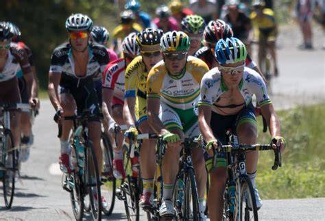 A Group Of People Riding Bikes Down A Road