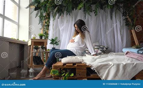 Attractive Pregnant Woman Is Sitting In Bed And Holding Her Belly