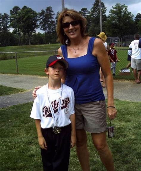 A Woman Standing Next To A Boy On Top Of A Field