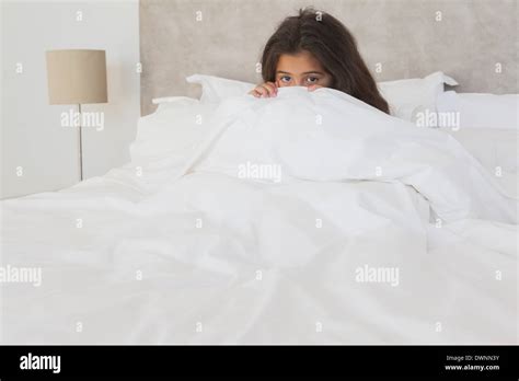 Girl hiding face behind sheet in bed Stock Photo - Alamy