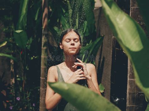 Woman Body In A Swimsuit Takes A Tropical Shower Outdoors Against The Backdrop Of Green