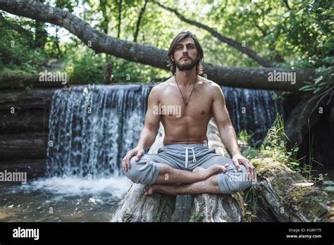 Shirtless Mann Sitzen Mit Gekreuzten Beinen Auf Logs Mit Wasserfall Im