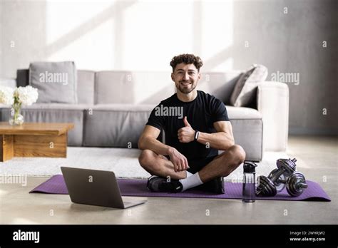 Mature Male Teacher Sitting On Mat At Home With Laptop Giving Online Yoga Class Stock Photo Alamy