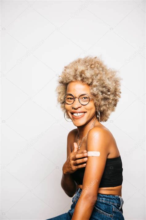 Retrato de una joven latina negra mostrando la tirita en su brazo después de la vacunación de