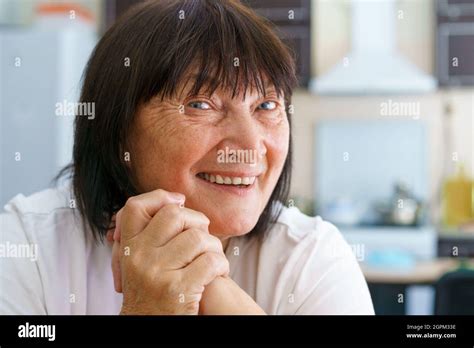 Close Up Portrait Of Smiling Mature Woman Sitting On Cozy Sofa At Home Posing For A Picture