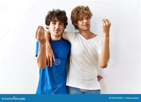 Joven Pareja Gay Parado Juntos En Un Contexto Aislado Haciendo Gesto Italiano Con Expresión