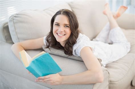 Premium Photo Cheerful Pretty Woman Lying On A Cosy Couch Reading Book