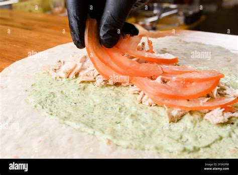 Proceso de cocción de burritos El cocinero añade tomate a la carne en