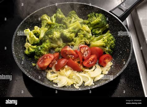 Onions Tomatoes And Broccoli Are Sauteed In A Steaming Frying Pan On