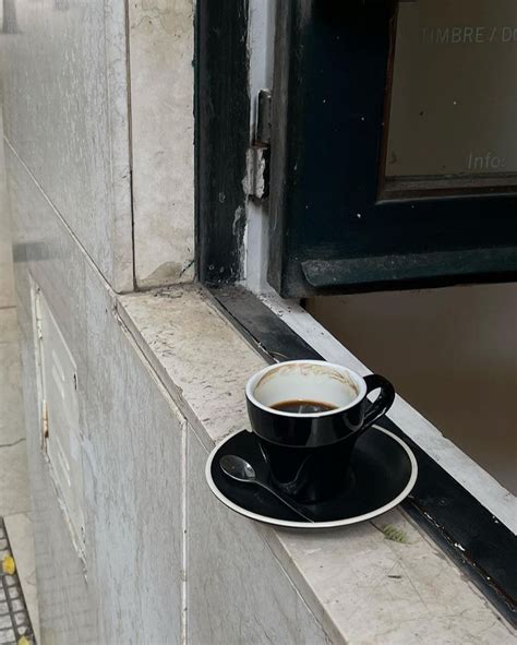 A Cup Of Coffee Sitting On Top Of A Black Saucer Next To A Window