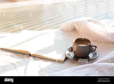 Aromatic morning coffee and open book on bed indoors Stock Photo - Alamy