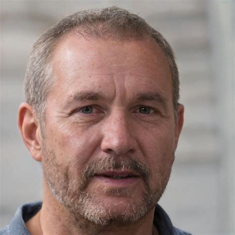 A Close Up Of A Person Wearing A Blue Shirt And Grey Hair With A Beard