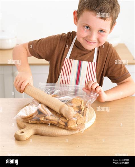 Boy Crushing Biscuits In A Bag Using A Rolling Pin 8 Years Stock Photo