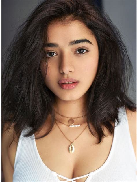 A Close Up Of A Person Wearing A White Shirt And Necklace With A Gold