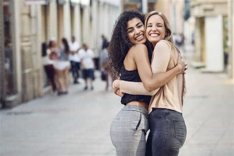 Portrait Of Two Happy Friends Hugging Each Other On The Street Stock Photo