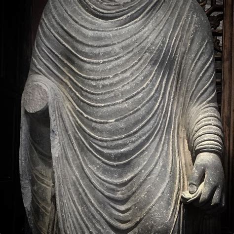 A Large Stone Buddha Statue Sitting On Top Of A Wooden Floor Next To A