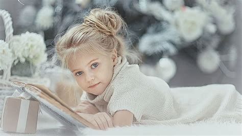 Cute Little Girl Is Lying Down On White Fur Cloth Wearing White Dress