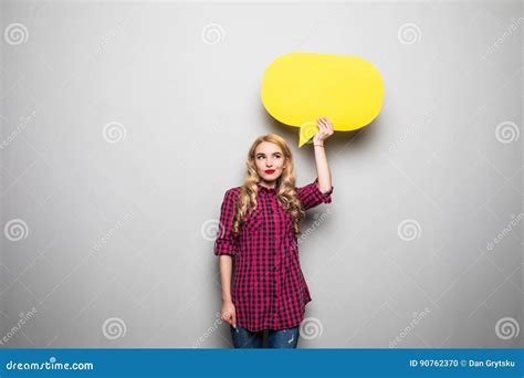 Belle Jeune Femme Blonde Tenant La Bulle Vide Jaune De La Parole Au Dessus Du Fond Gris Photo