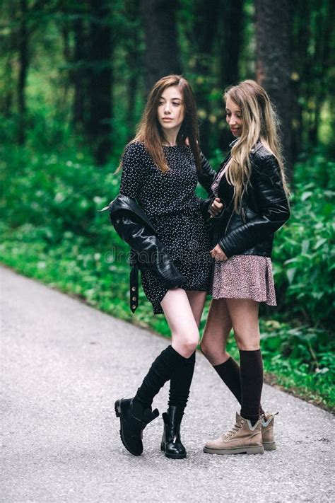 Two Girls Blonde And Brunette On The Road In The Summer Forest Stock