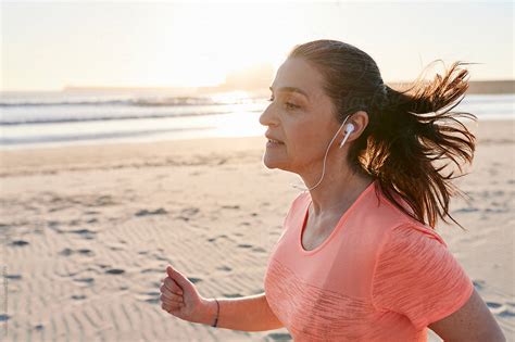 Mature Woman Running On A Beach At Dusk By Stocksy Contributor Ivan Gener Stocksy