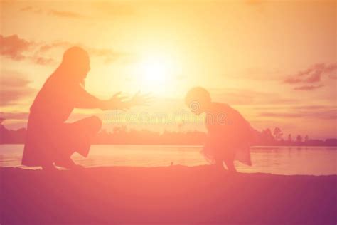 Silhouettes Of Mother And Little Daughter Walking At Sunset Stock Photo