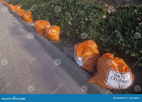 Bright Orange Trash Bags Along A Roadway Waiting For Pickup Editorial