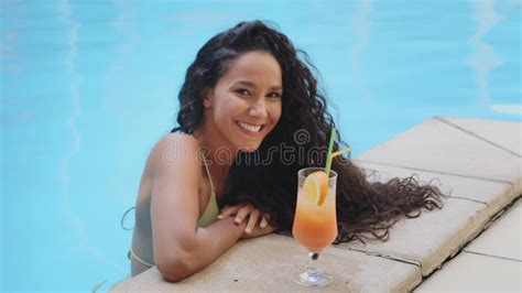 Seductive Hispanic Curly Brunette Girl In Swimsuit Drink Cocktail Looking At Camera Winks Smile