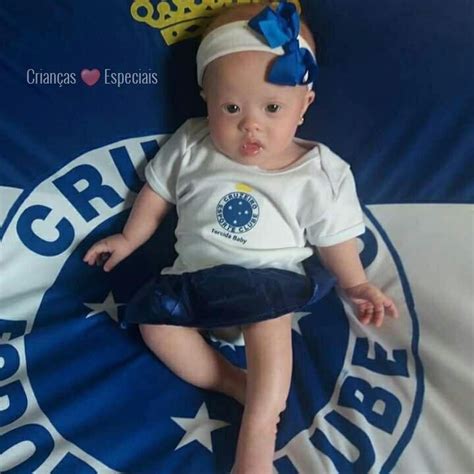 A Baby Wearing A Crown Sitting On Top Of A Blue And White Bed Sheet