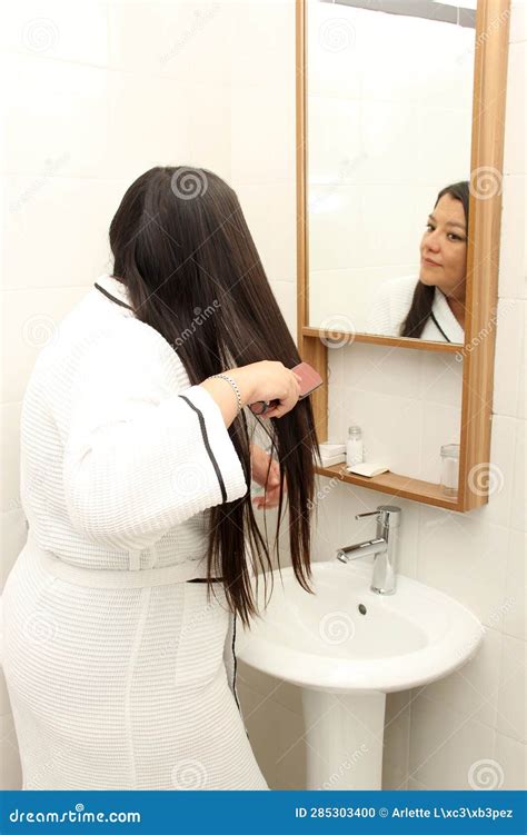 Year Old Latina Woman Cares And Brushes Hair In The Bathroom In A Bathrobe In Front Of The