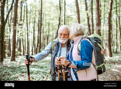 Beautiful Senior Couple Hiking With Backpacks And Trekking Sticks In