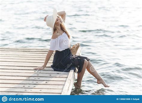 Portrait Of A Cute Girl Outdoors In Sitting On A Pier In The Spring