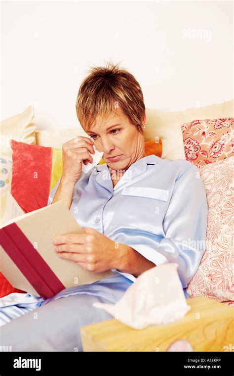 Mature Woman Lying In Bed And Reading A Book Stock Photo Alamy