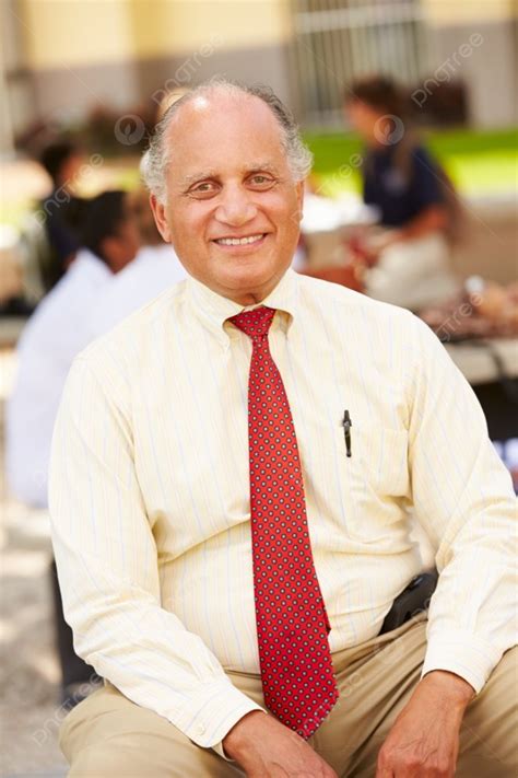 Portrait Of High School Teacher Sitting On School Campus Background And