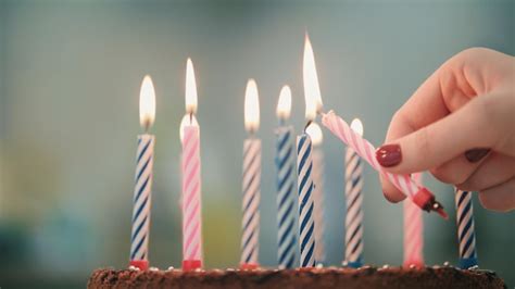 A mão da mulher colocou a chama da vela no bolo de aniversário vela