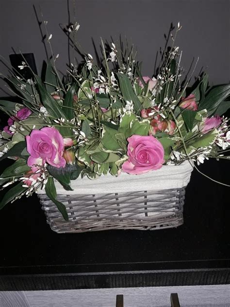 A Basket Filled With Pink Roses On Top Of A Table