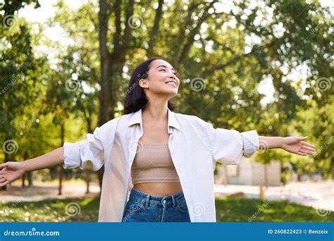 Portrait Of Carefree Young Asian Woman Dancing In Park Alone Enjoying