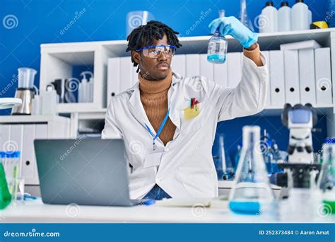 African American Man Scientist Using Laptop Measuring Liquid At