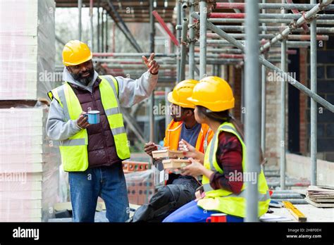 Construction Workers Enjoying Lunch Break At Construction Site Stock