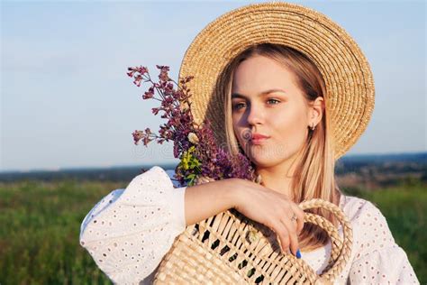 Portrait De Belle Fille Blonde Dans Le Chapeau De Paille Et Avec Le Bouquet De Fleurs Sauvages
