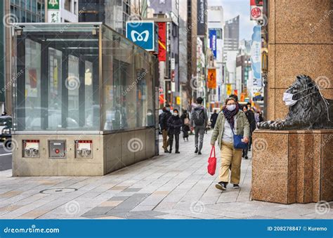 Pedestrian Looking at the Lion Statue Wearing a Mask at Mitsukoshi ...