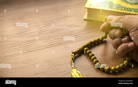 selective focus  hand counting rosary beads  quran  wooden