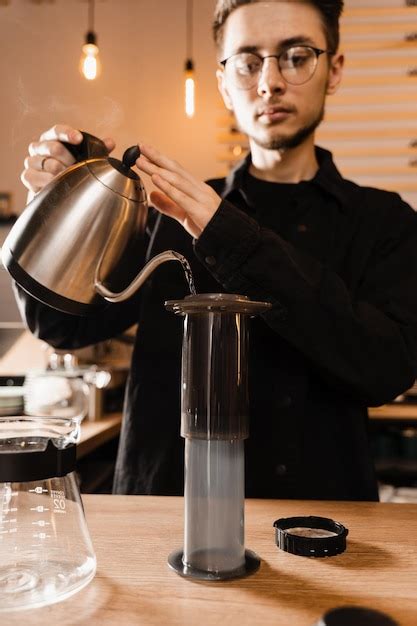 O barista está despejando água quente da chaleira para o aeropress