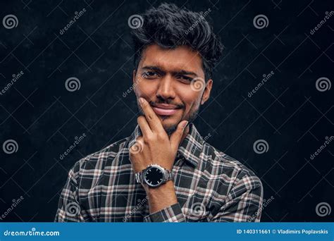 Close Up Portrait Of A Handsome Indian Man Wearing A Plaid Shirt Posing With Hand On Chin Stock