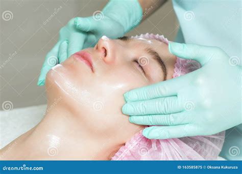 Cosmetologist Is Applying A White Cream On Woman`s Face Stock Image