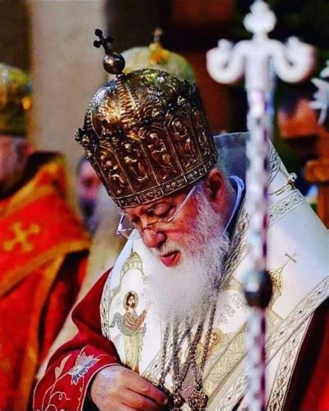 An Old Man With A Beard Wearing A Crown And Holding A Cell Phone In His