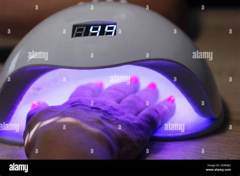 Woman Hand Inside UV LED Lamp For Drying Pink Nails With Gel Method