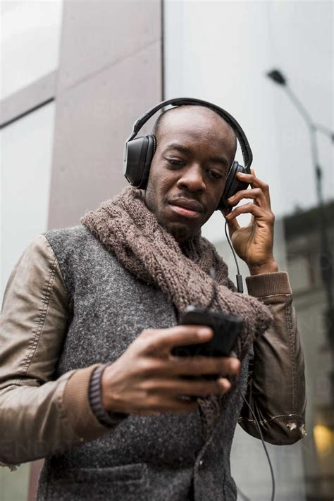 Bald Man Listening Music With Headphones Looking At Cell Phone Stock Photo