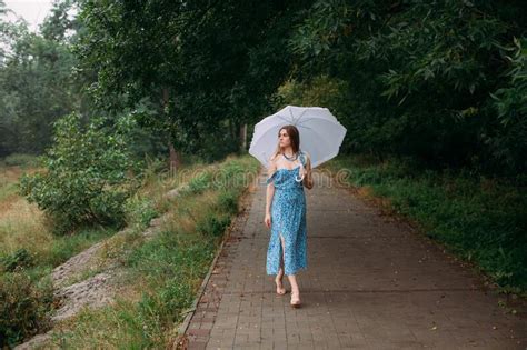 Girl With Blond Long Hair In A Blue Summer Dress And Shoes Walking