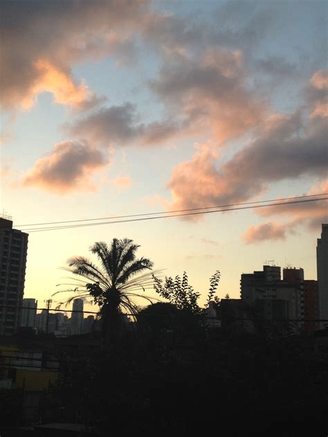 The Sun Is Setting Behind Some Buildings And Palm Trees In The