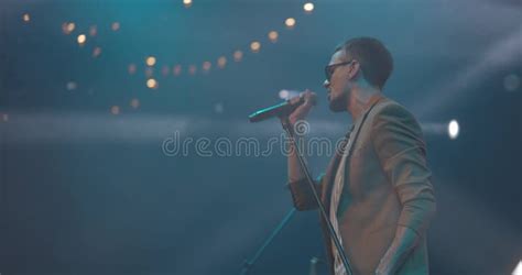 Side View Of Men Singing To Microphone On Light Background Stylish